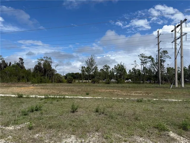 Expansive undeveloped land featuring natural vegetation and overhead electrical infrastructure