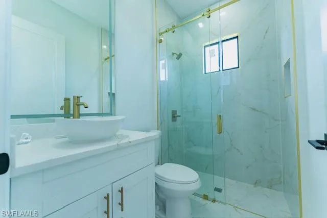 Bathroom with vanity and a marble finish shower