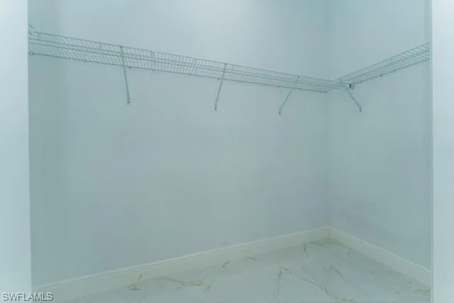 Walk in closet featuring marble finish flooring