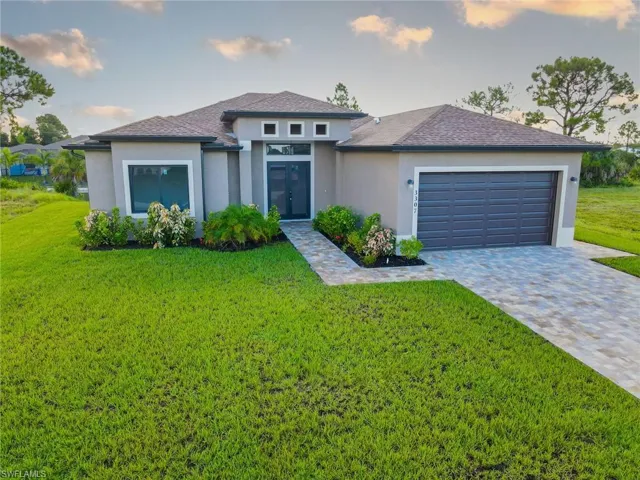 Prairie-style home with stucco siding, a front lawn, decorative driveway, a shingled roof, and a garage