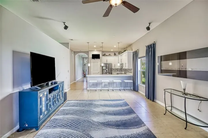 Living area with light tile patterned floors, arched walkways, ceiling fan, and recessed lighting