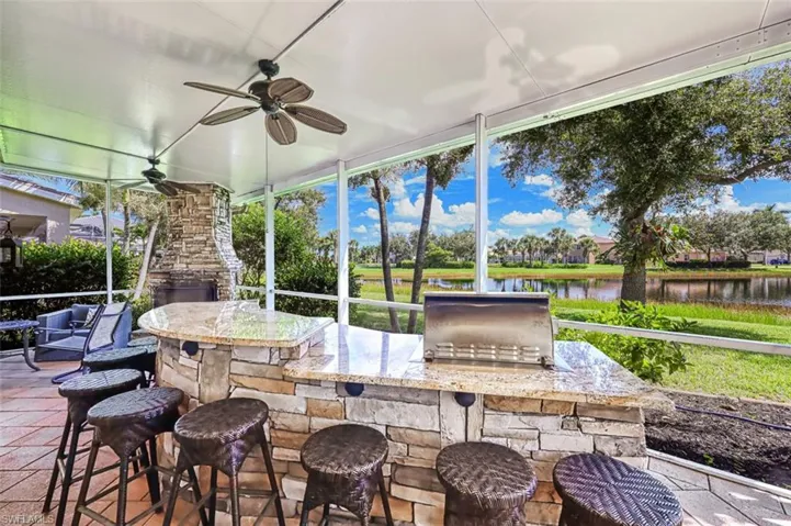 Sunroom / solarium with a water view, area for grilling, a ceiling fan, and exterior bar