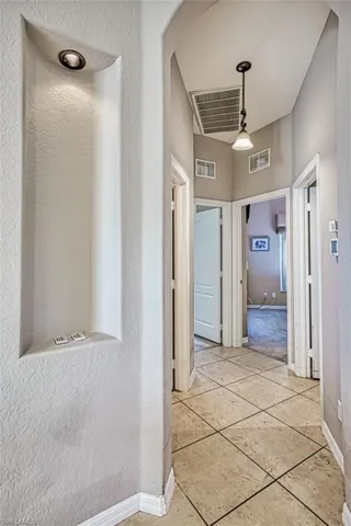 Hall featuring light tile patterned floors and a textured wall