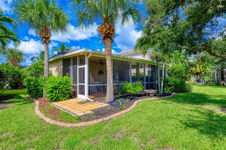 Back of house with stucco siding, ceiling fan, a sunroom, and a yard