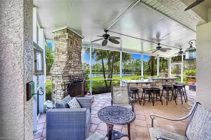 View of patio with a sunroom, a water view, ceiling fan, and an outdoor stone fireplace