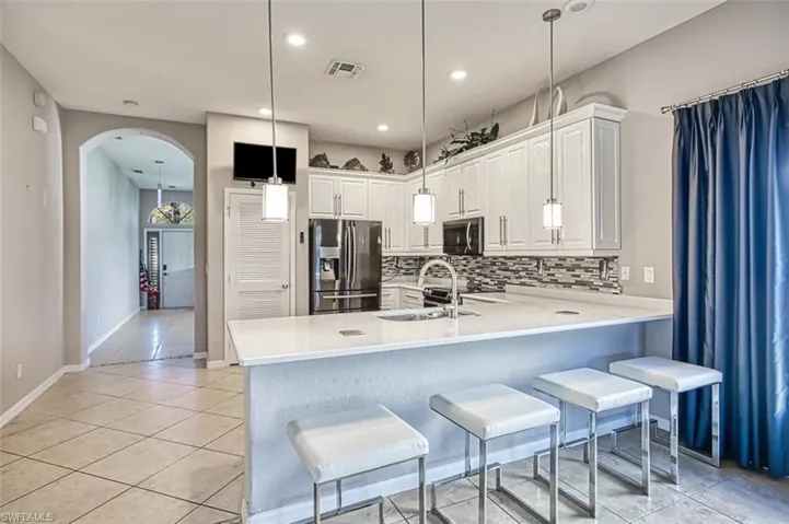 Kitchen with a breakfast bar area, light tile patterned flooring, appliances with stainless steel finishes, arched walkways, and recessed lighting