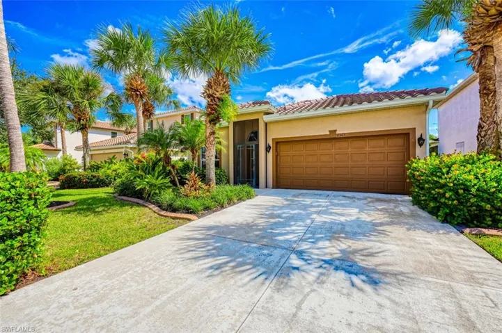 Mediterranean / spanish house featuring stucco siding, driveway, a tiled roof, a garage, and a front lawn