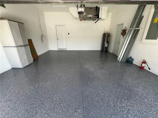 Garage with electric panel, water heater, and a garage door opener