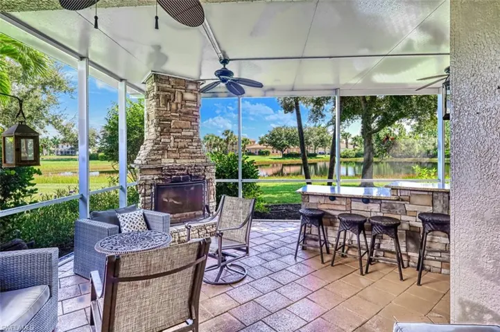 Sunroom featuring an outdoor stone fireplace, a water view, plenty of natural light, and a patio