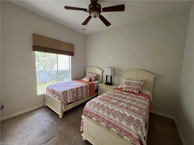 Carpeted bedroom featuring ceiling fan and baseboards