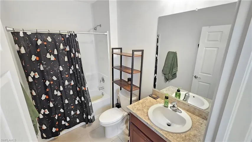 Full bath featuring shower / bathtub combination with curtain, vanity, toilet, and tile patterned floors