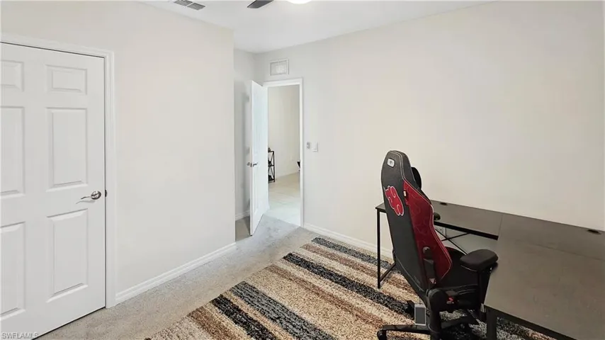 Office space featuring a ceiling fan, light carpet, visible vents, and baseboards