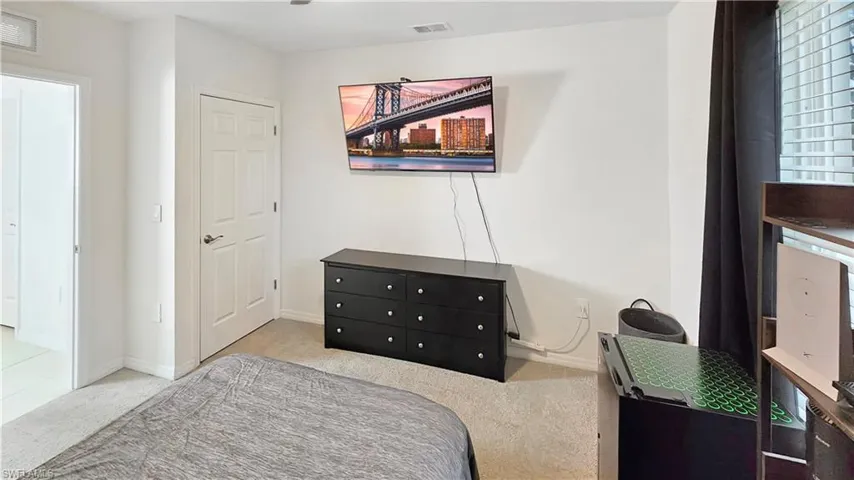 Bedroom with baseboards, visible vents, and light colored carpet