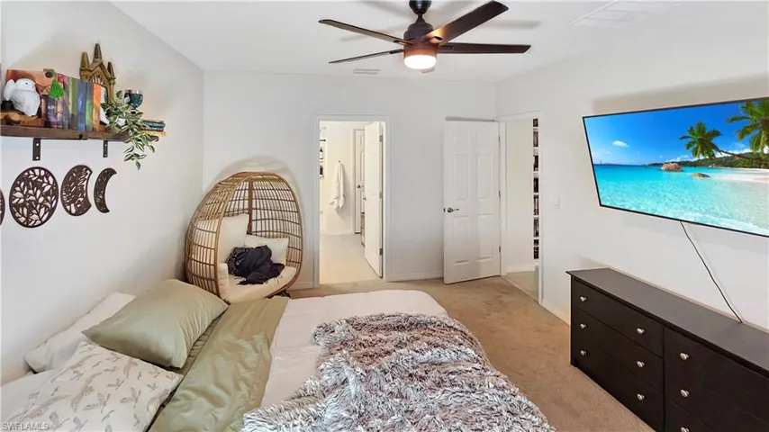 Bedroom with light colored carpet, visible vents, a ceiling fan, connected bathroom, and baseboards