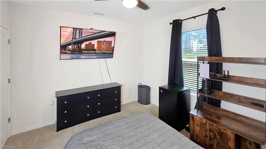Bedroom with baseboards, visible vents, ceiling fan, and light colored carpet