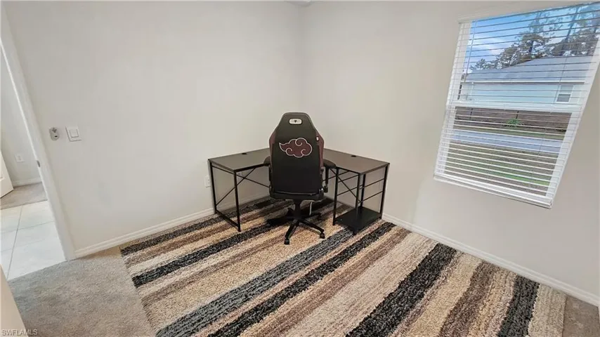 Home office featuring light carpet, light tile patterned floors, and baseboards
