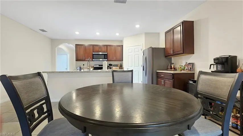 Kitchen featuring light tile patterned floors, visible vents, arched walkways, appliances with stainless steel finishes, and recessed lighting