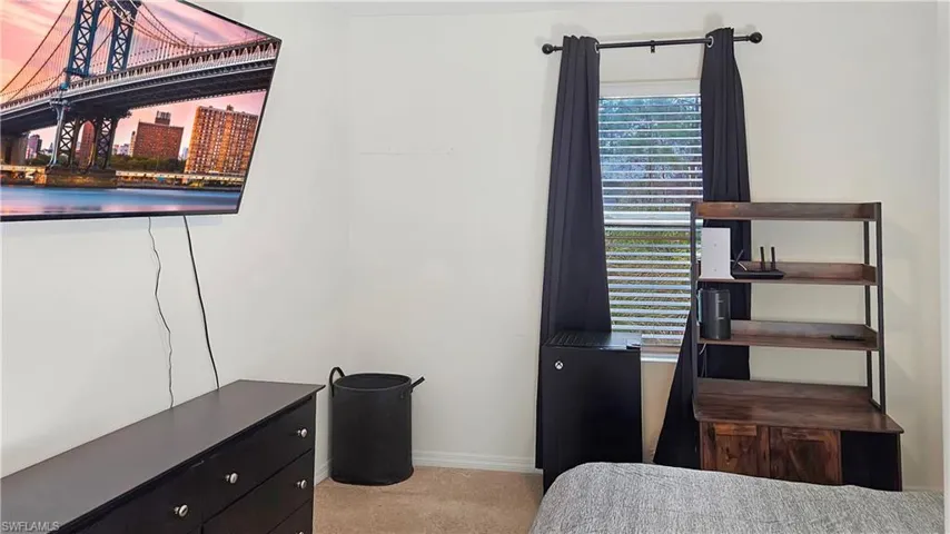 Bedroom featuring light carpet and baseboards