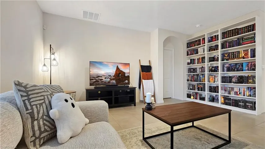 Sitting room featuring built in features, arched walkways, light tile patterned flooring, and visible vents