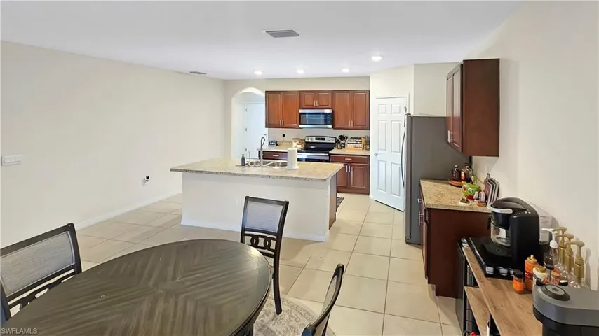 Kitchen with light tile patterned floors, arched walkways, a sink, visible vents, and appliances with stainless steel finishes