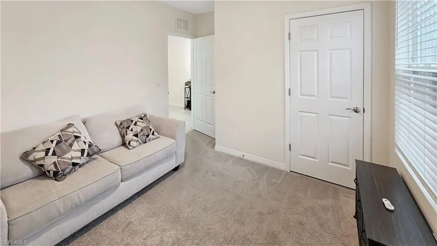 Living area with light carpet, visible vents, and baseboards