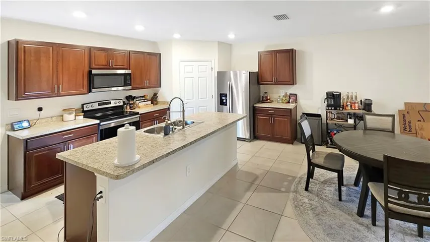 Kitchen featuring light countertops, visible vents, appliances with stainless steel finishes, a sink, and an island with sink