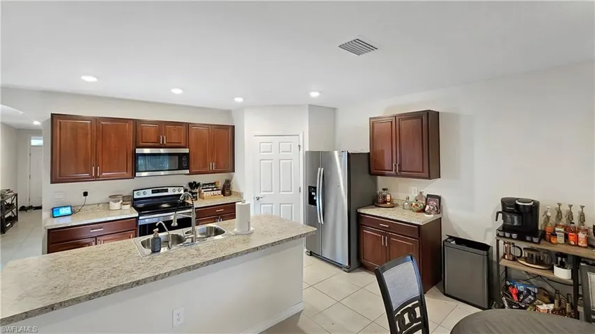 Kitchen featuring stainless steel appliances, a sink, visible vents, light countertops, and an island with sink
