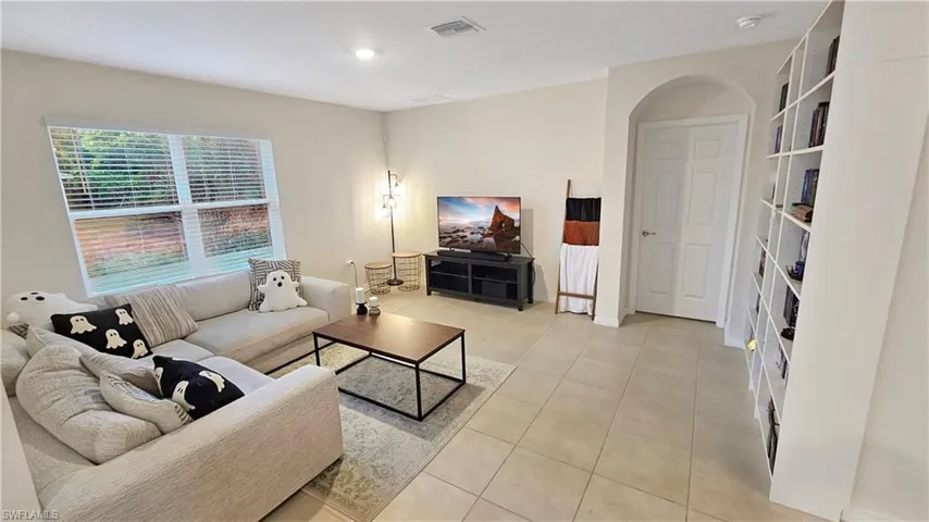 Living area with light tile patterned floors, visible vents, and baseboards