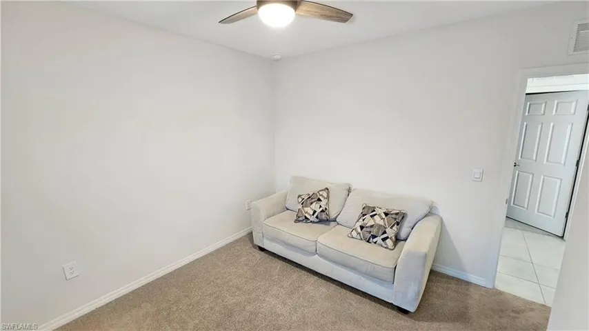 Living area featuring light carpet, ceiling fan, and baseboards