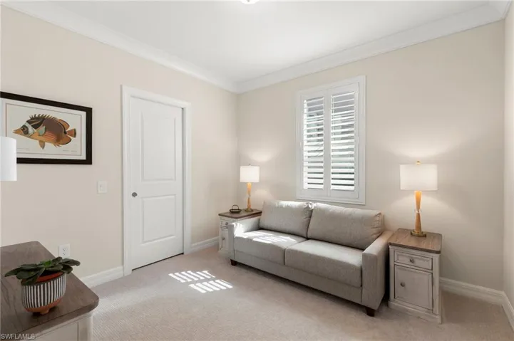 Living area with crown molding, baseboards, and light carpet