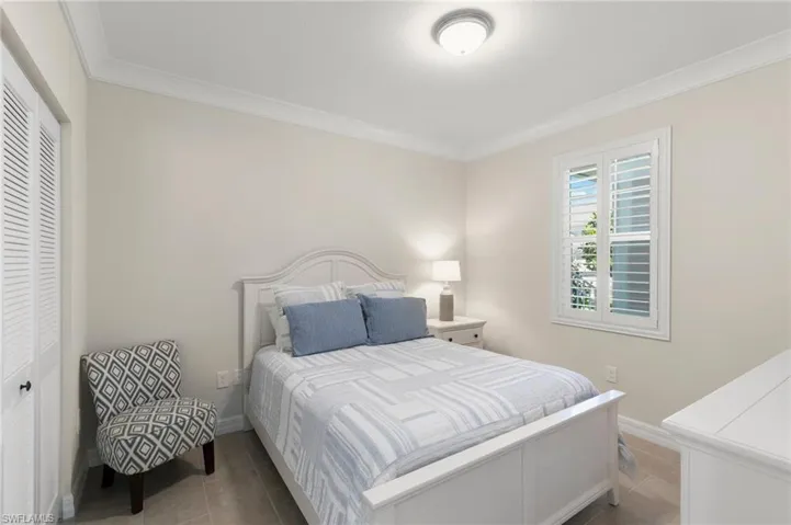 Bedroom with a closet, baseboards, ornamental molding, and tile patterned flooring