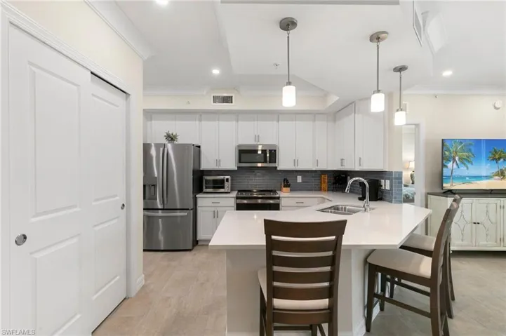 Kitchen with a sink, visible vents, appliances with stainless steel finishes, and decorative backsplash
