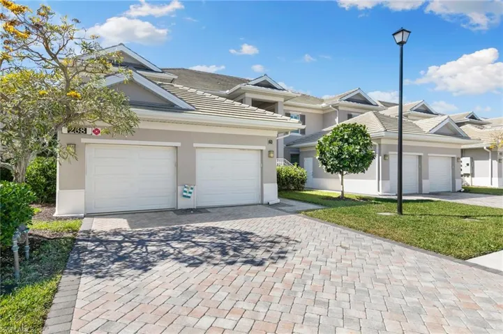 View of front facade with stucco siding, an attached garage, a tile roof, and decorative driveway