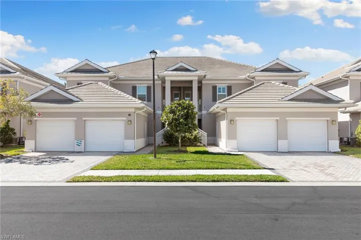 View of front of property with stucco siding, a front lawn, a garage, a tile roof, and decorative driveway