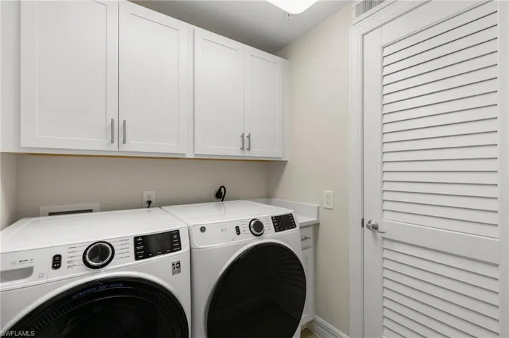 Laundry room with washing machine and clothes dryer, cabinet space, and baseboards