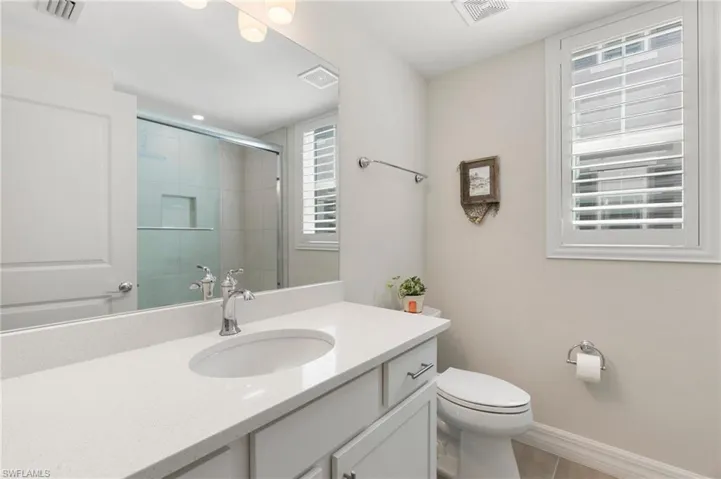 Bathroom with visible vents, a stall shower, and toilet