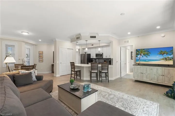 Living area with visible vents, baseboards, and ornamental molding