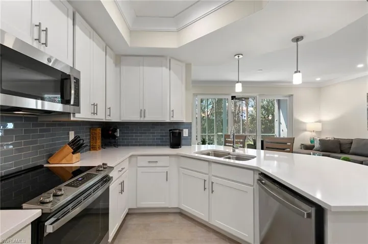 Kitchen with ornamental molding, a sink, a peninsula, appliances with stainless steel finishes, and light countertops