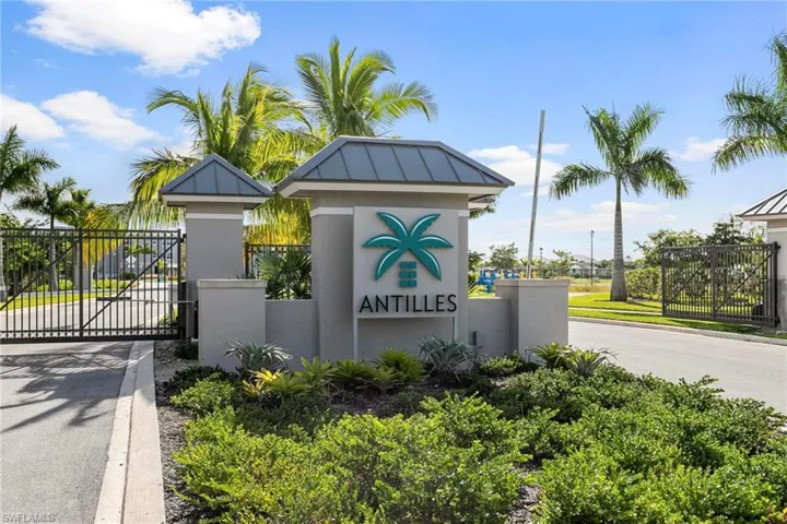 Community sign featuring a gate, fence, and driveway