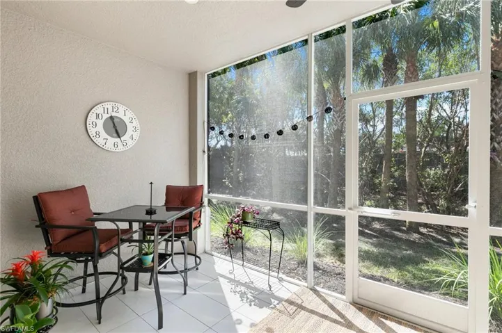 Sunroom featuring a wall of windows, tile patterned flooring, and a textured wall