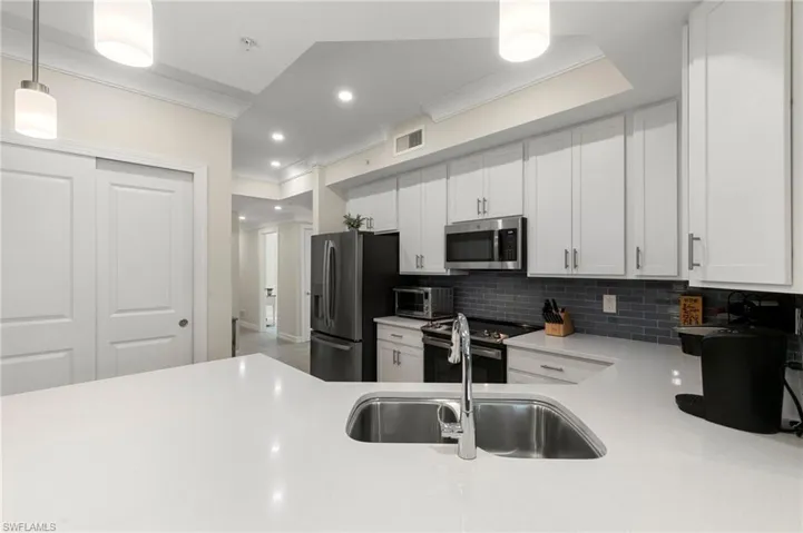 Kitchen with light countertops, visible vents, tasteful backsplash, and stainless steel appliances