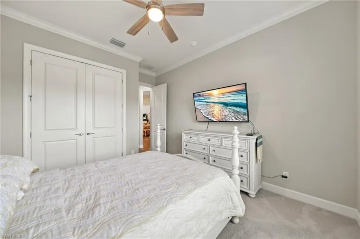 Neutral wall tones, ceiling fan with integrated lighting, crown molding, and double-door reach-in closet