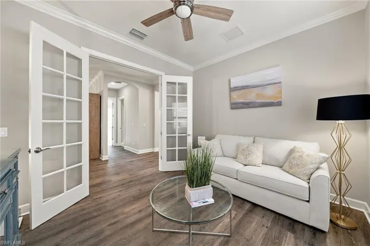 Room featuring wood-finish flooring, crown molding, French doors with glass panes, and a ceiling fan