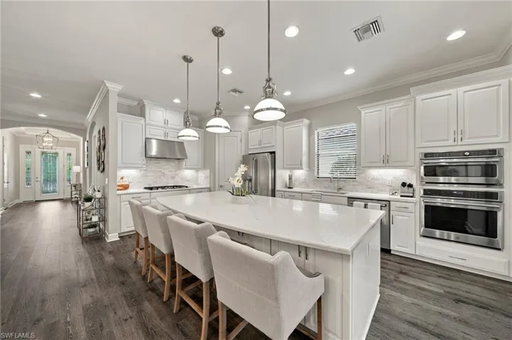 Kitchen featuring white shaker-style cabinetry, a quartz-topped center island, stainless steel double wall ovens, recessed lighting, and wood-finish flooring