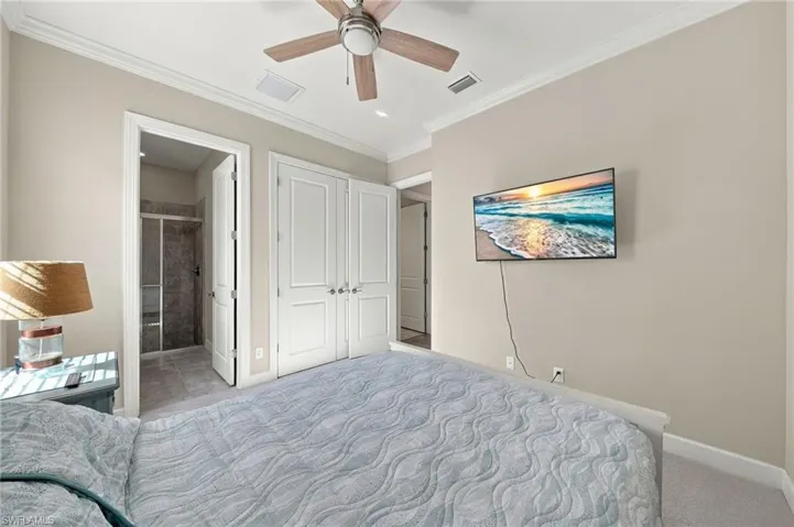 Neutral-toned interior featuring crown molding, double-panel closet doors, and a ceiling fan with light fixture