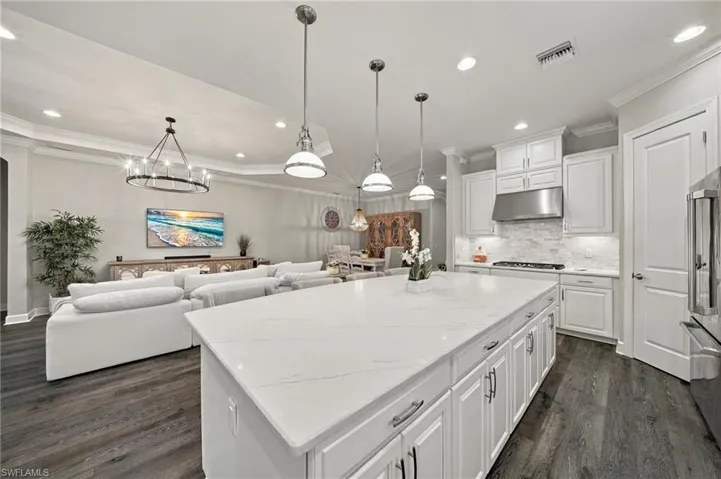 Kitchen featuring a large central island with quartz countertops, white cabinetry, stainless steel range hood, recessed lighting, and wood-finish flooring