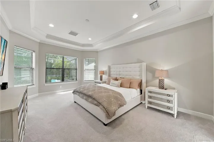 Tray ceiling with recessed lighting and neutral wall-to-wall carpeting