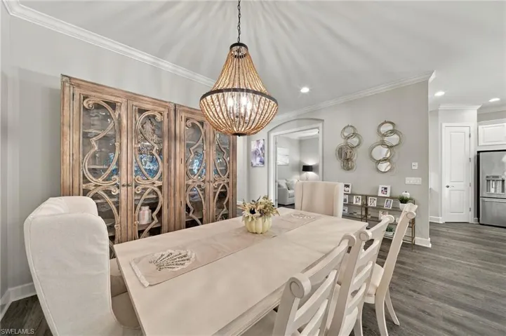Dining area featuring wood-finish flooring, a decorative beaded chandelier, and custom built-in cabinetry with ornate wood framework and glass-panel doors
