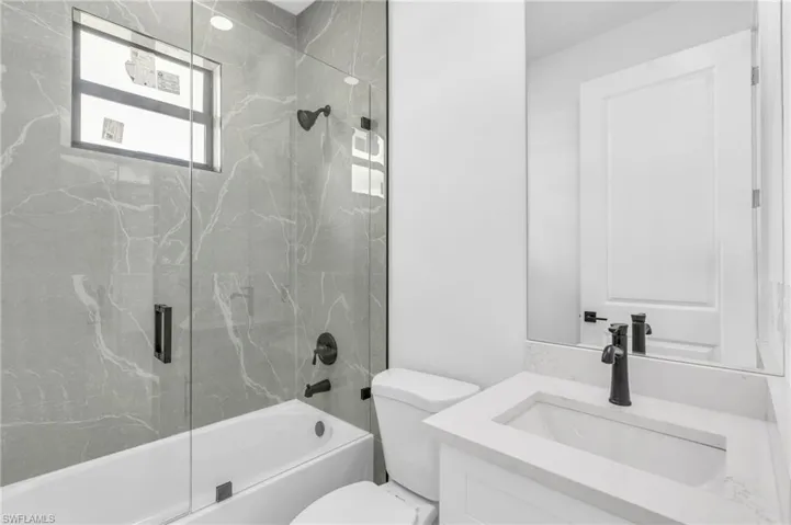Full bathroom featuring vanity, toilet, and combined bath / shower with glass door