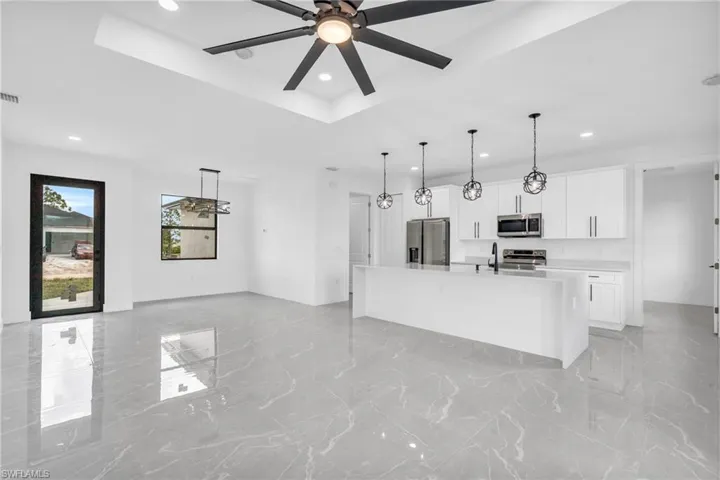 Kitchen featuring appliances with stainless steel finishes, a kitchen island with sink, sink, and white cabinets